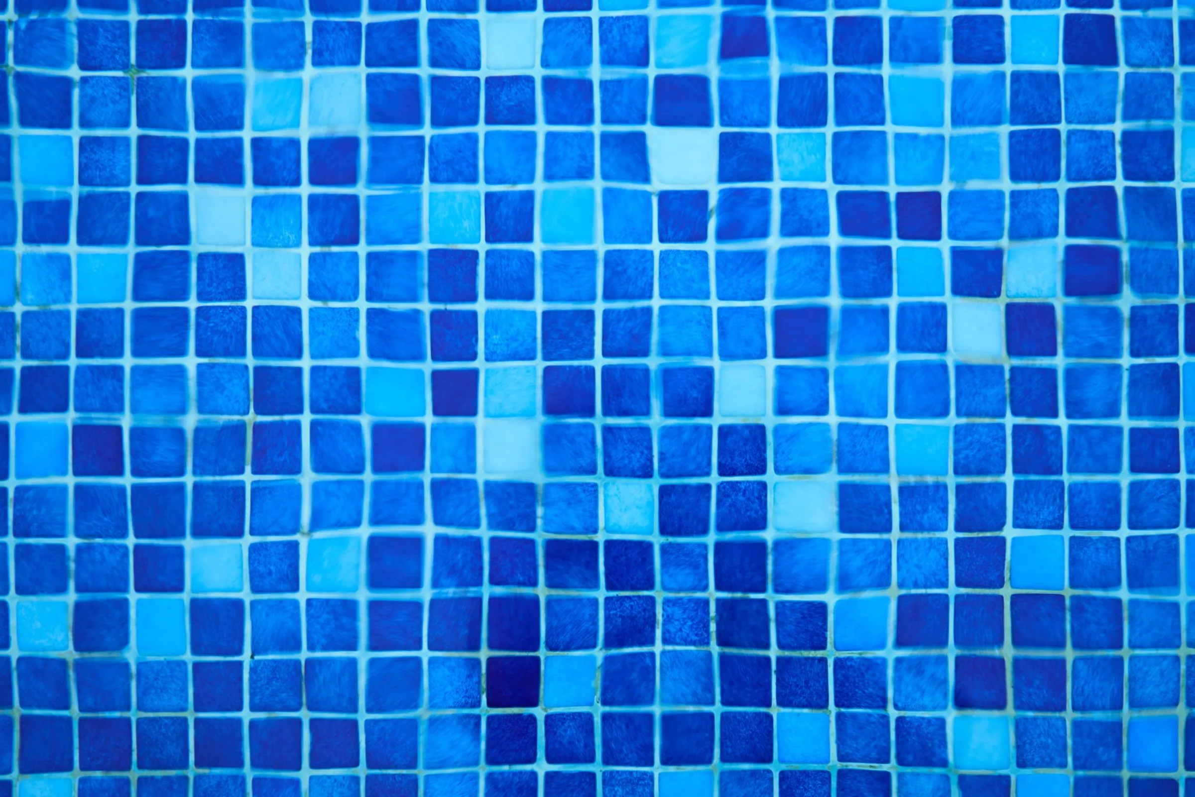 Close-up of small square blue mosaic tiles laid in a grid with visible grout lines